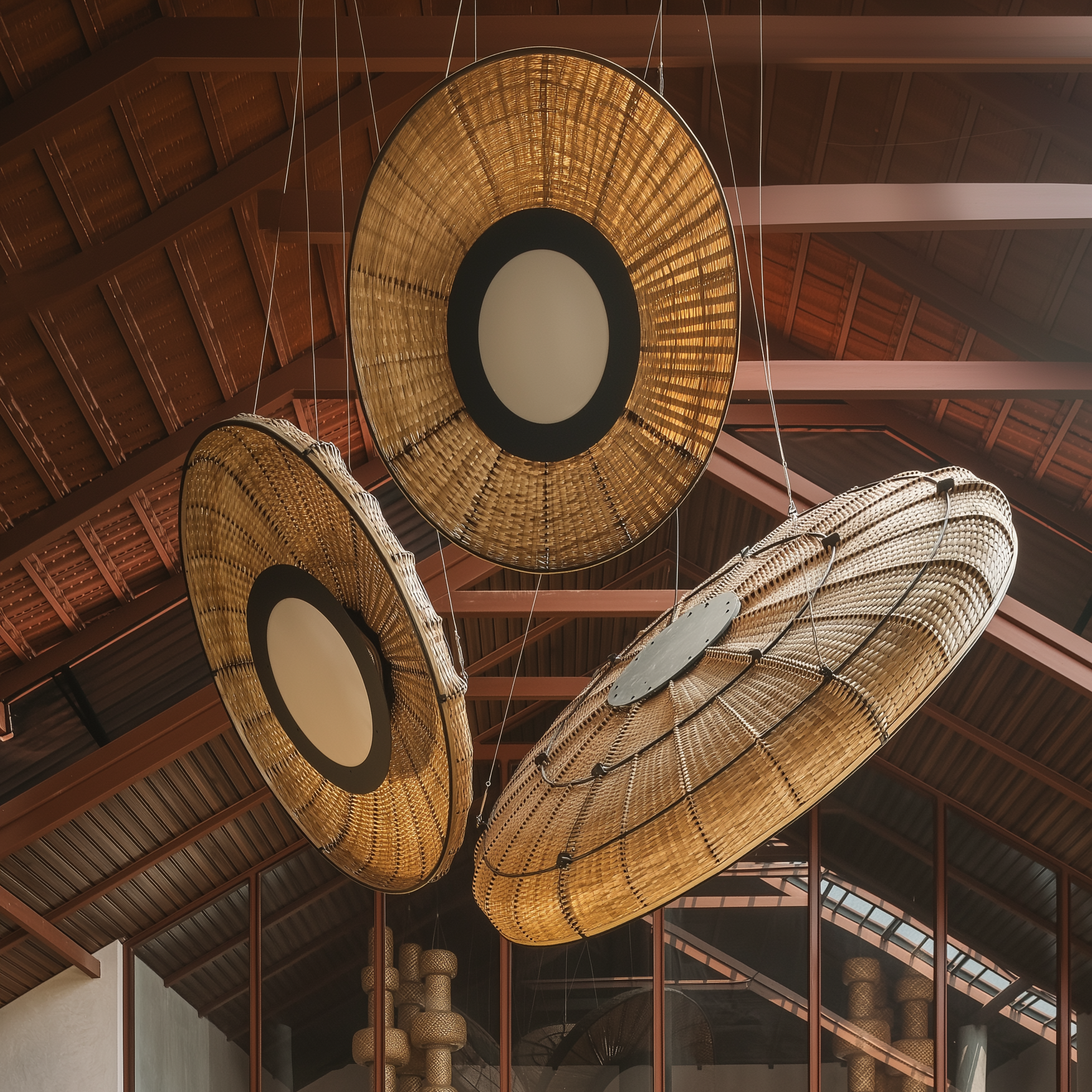 Large Lilypad bamboo chandeliers with a Japandi design, featuring woven natural textures and circular centers in a rustic interior.